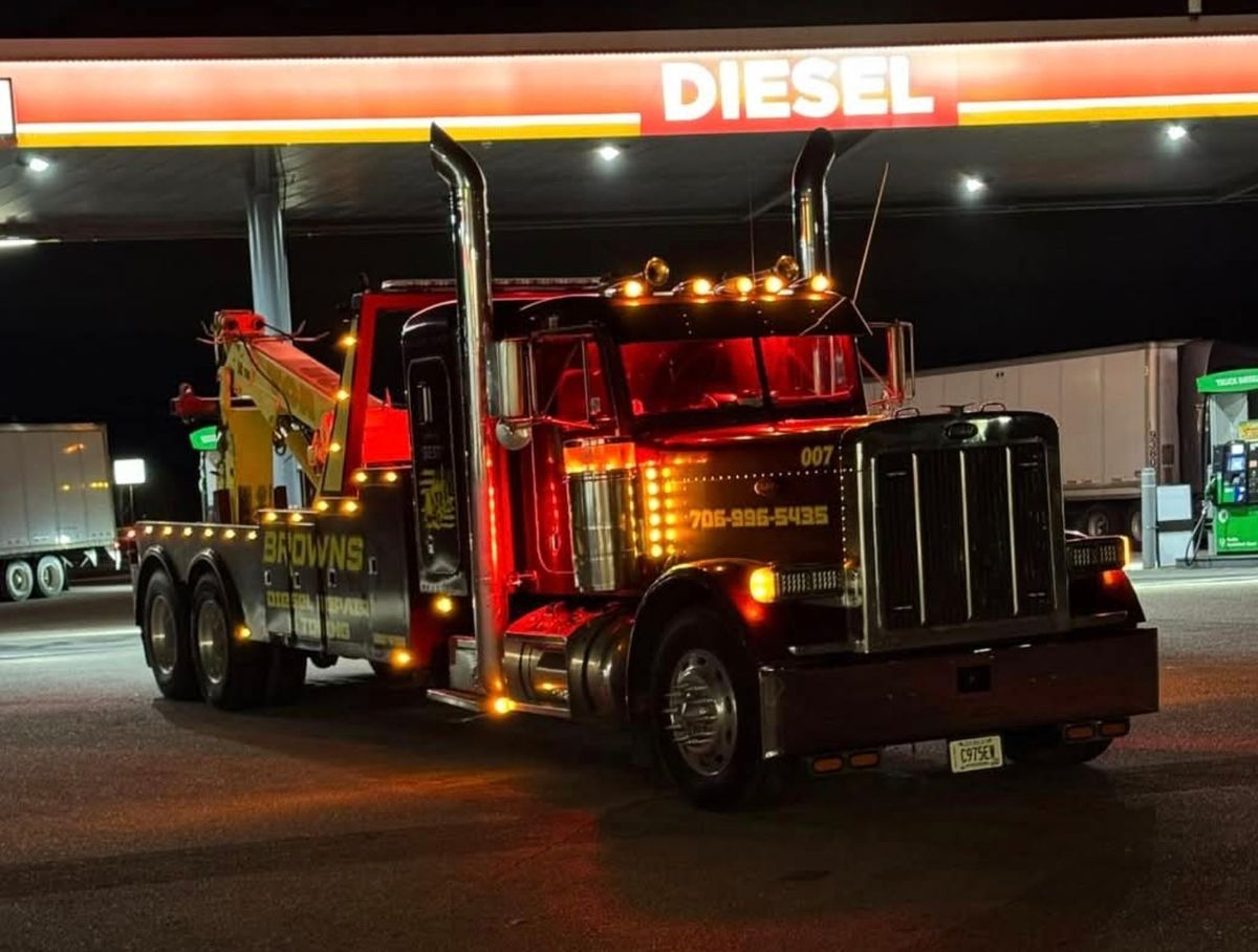 Brown's wrecker at a diesel fuel stop at night, with its amber and red lights lit.