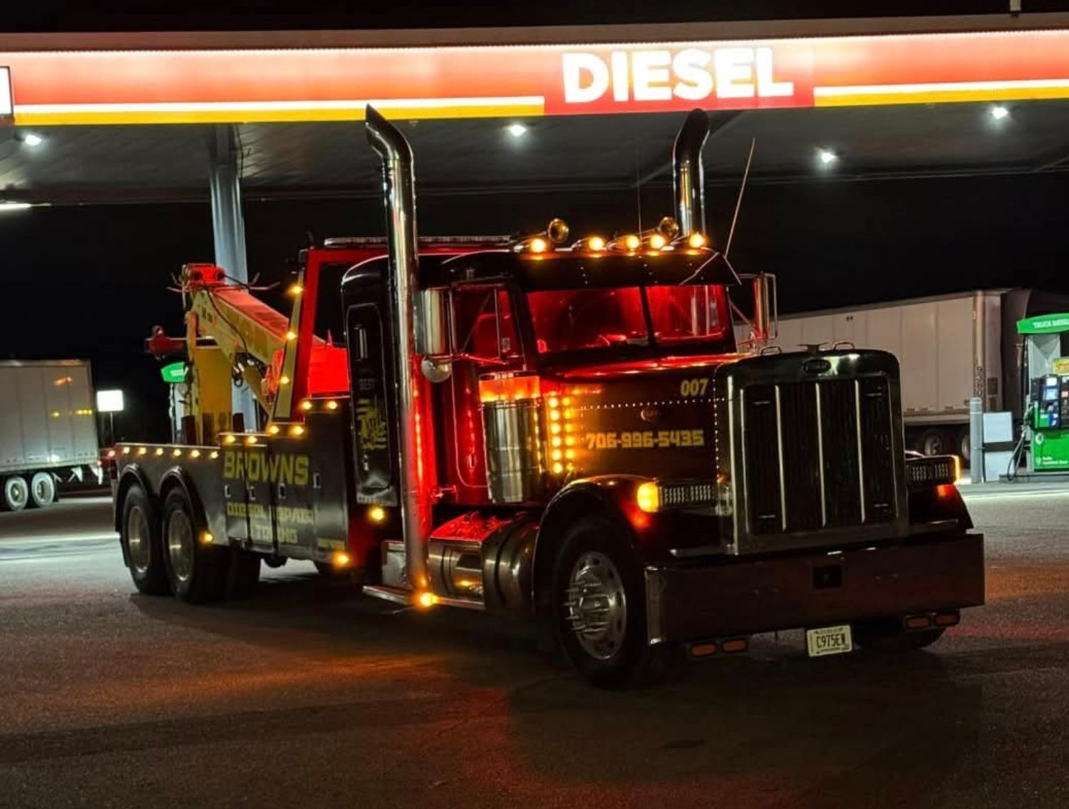 Brown's wrecker at a diesel fuel stop at night, with its amber and red lights lit.