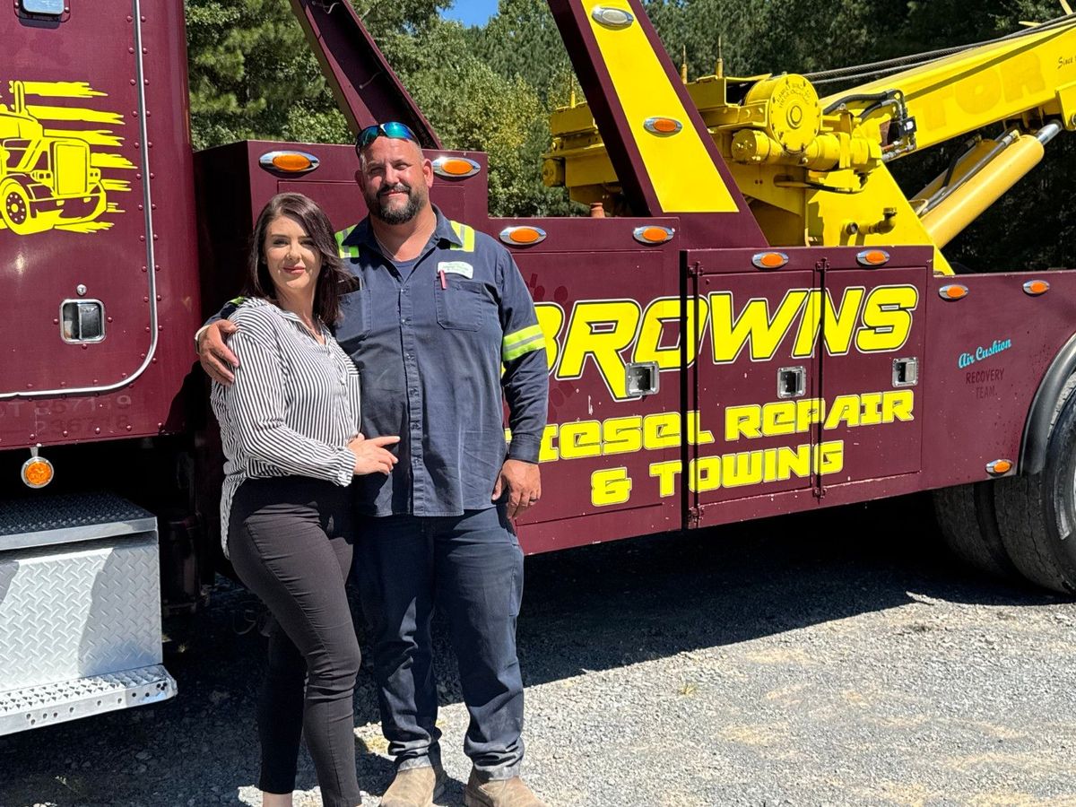 Chris Brown and his wife Ashley Brown standing beside a Brown's wrecker.